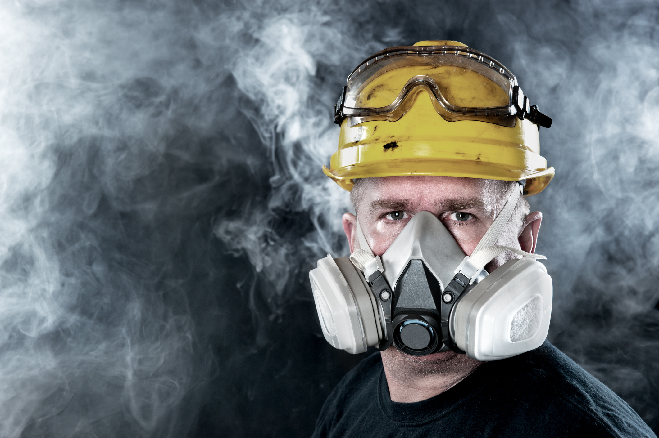 A rescue worker wears a respirator in a smokey, toxic atmosphere.  Image show the importance of protection readiness and safety.